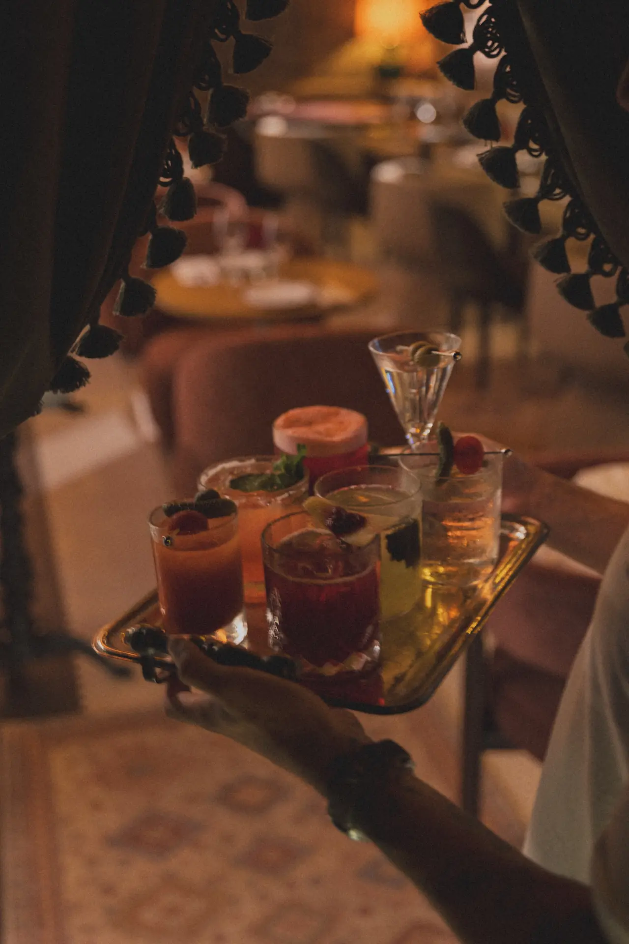 Garçom servindo uma bandeja de drinks no Bartô Secreto