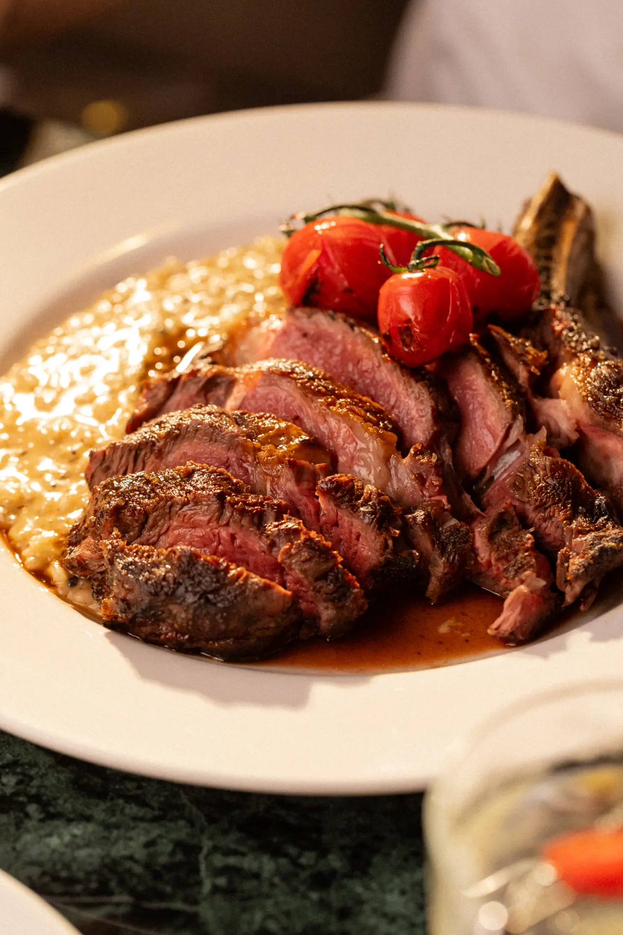 Carne fatiada ao ponto sobre risoto, com tomates confitados