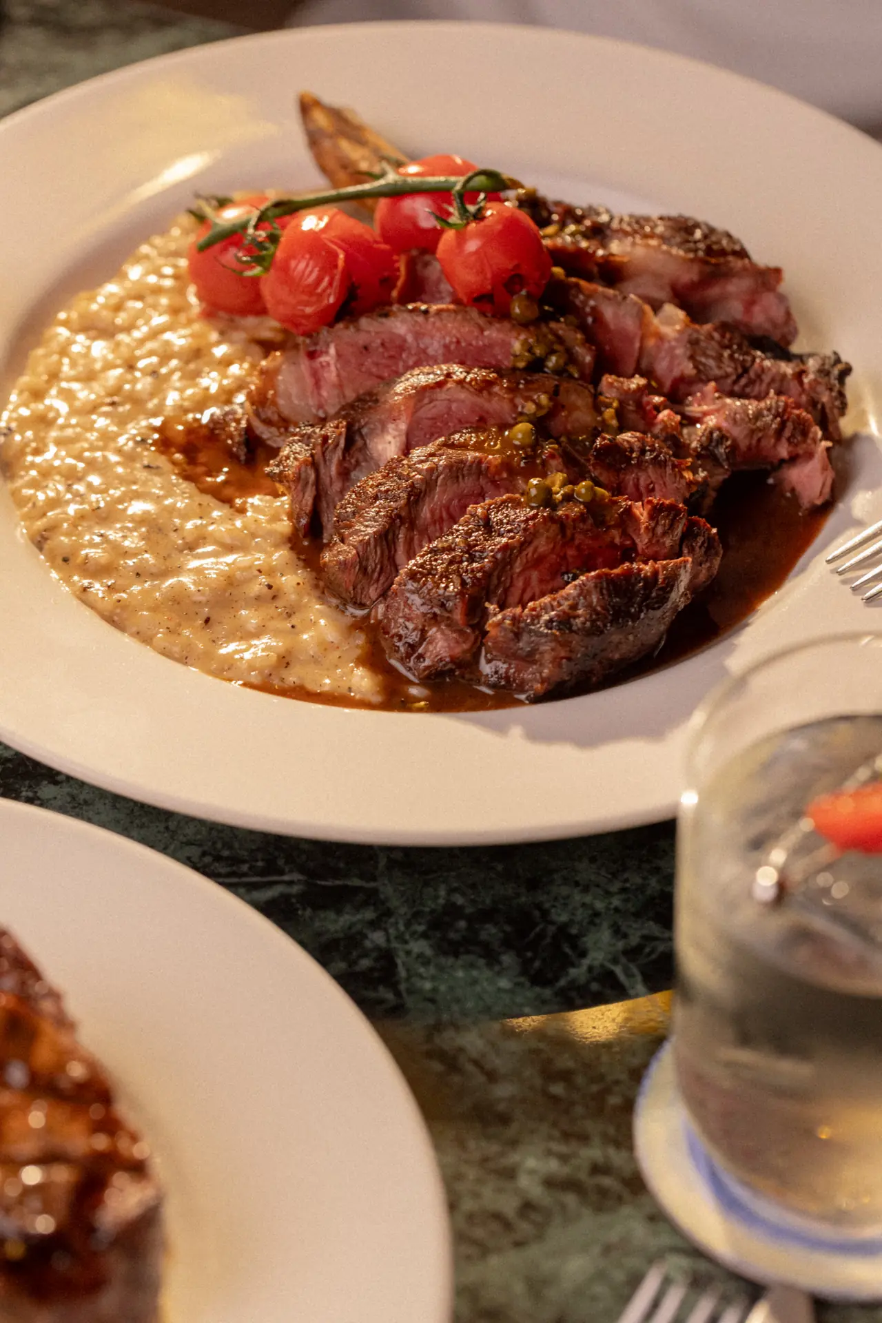 Carne fatiada com tomates confitados sobre risoto