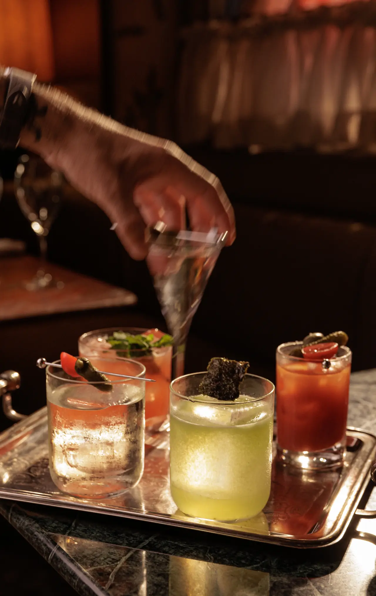Bandeja com quatro drinks coloridos sobre mármore verde