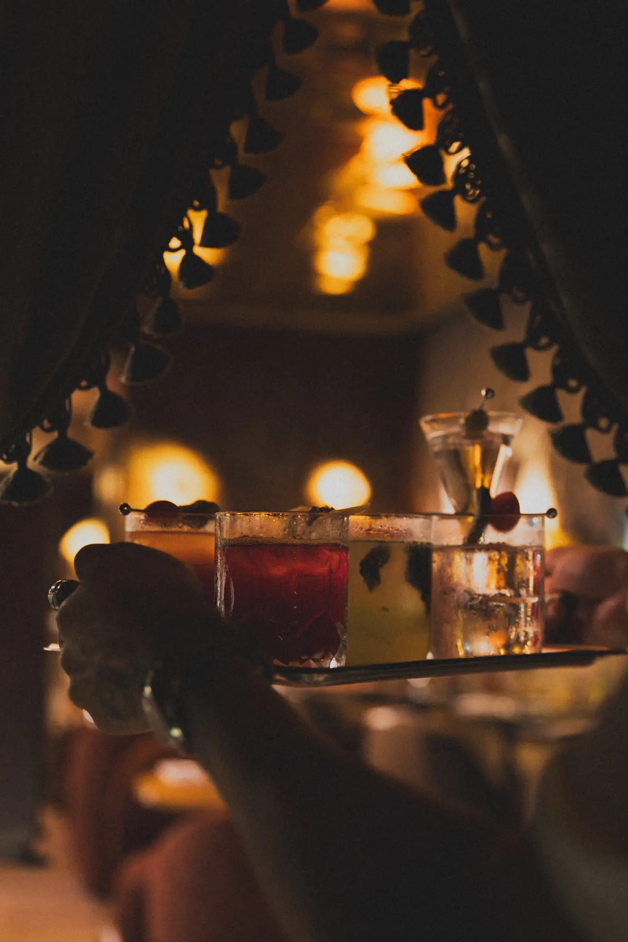 Bandeja com drinks vermelhos passando entre as mesas do Bartô Secreto
