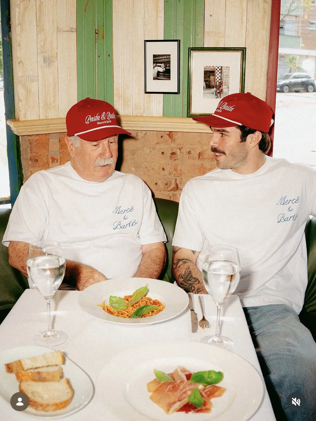 Dois homens de boné vermelho almoçando massa no Bartô