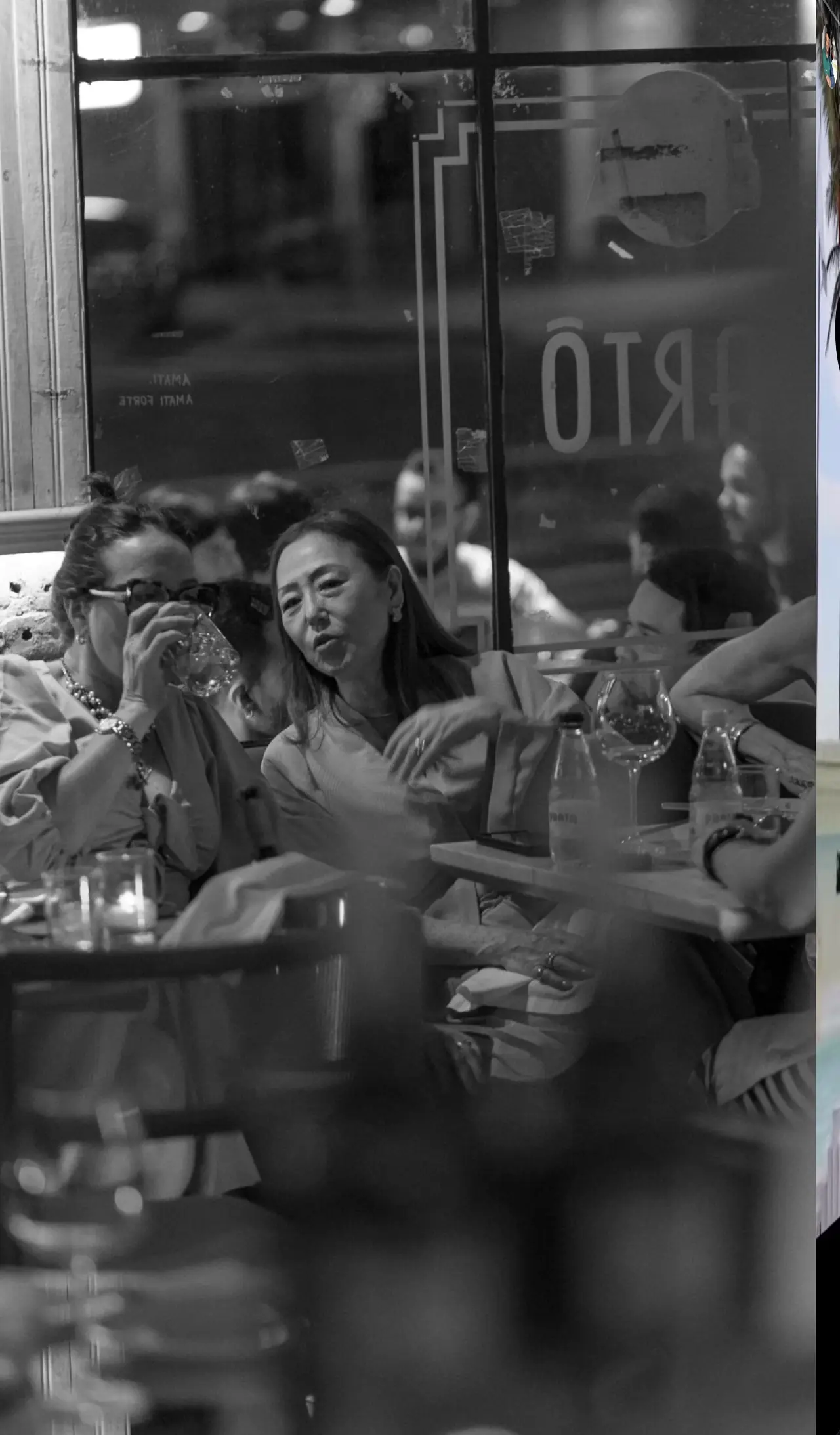 Clientes conversando e rindo em uma mesa do Bartô, em preto e branco