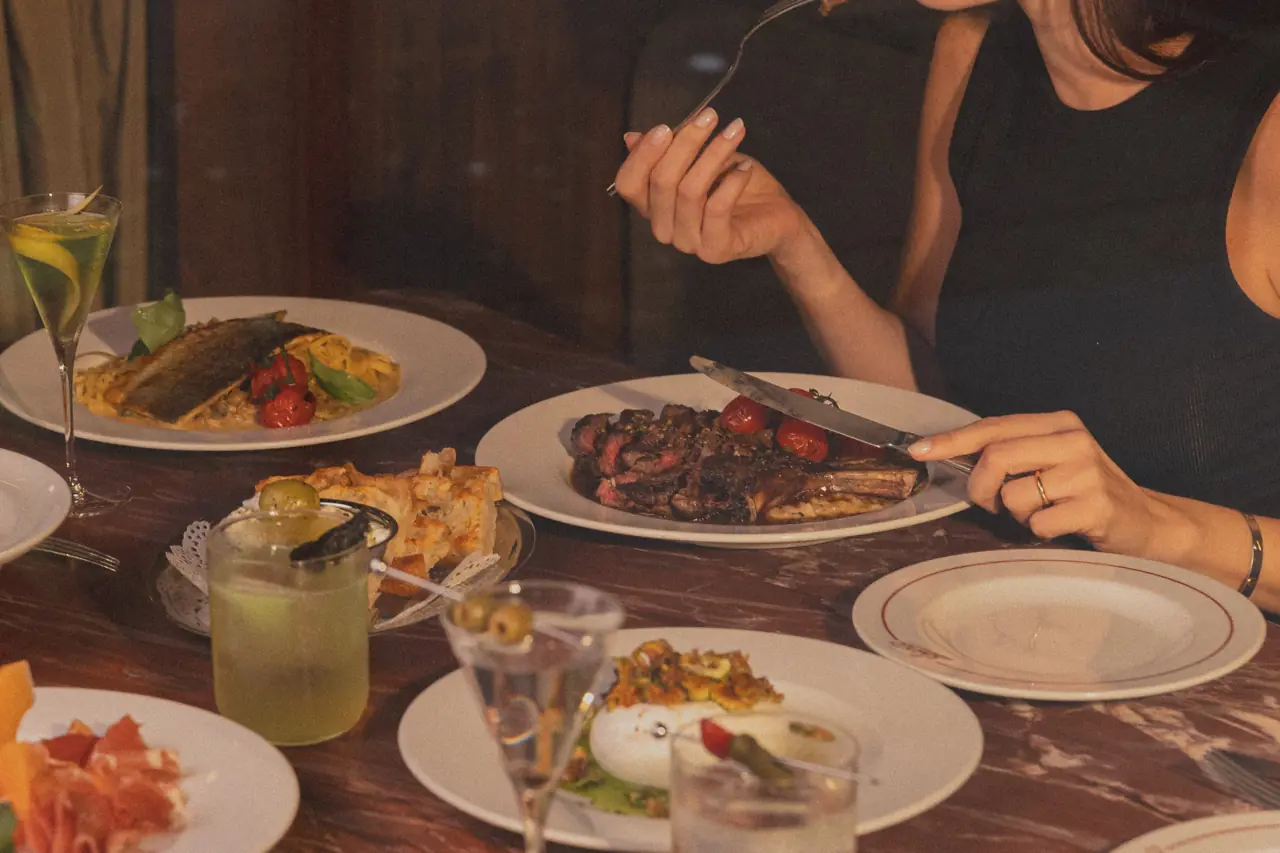 Casal jantando no Bartô com pratos e drinks na mesa