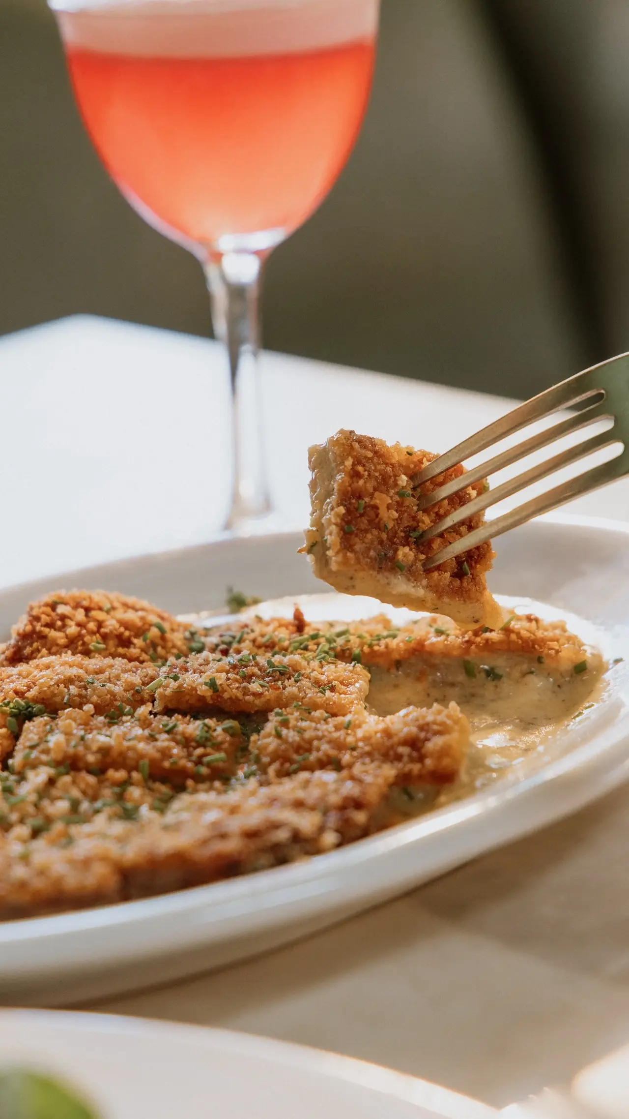 Prato à milanesa com taça de vinho rosé no Bartô