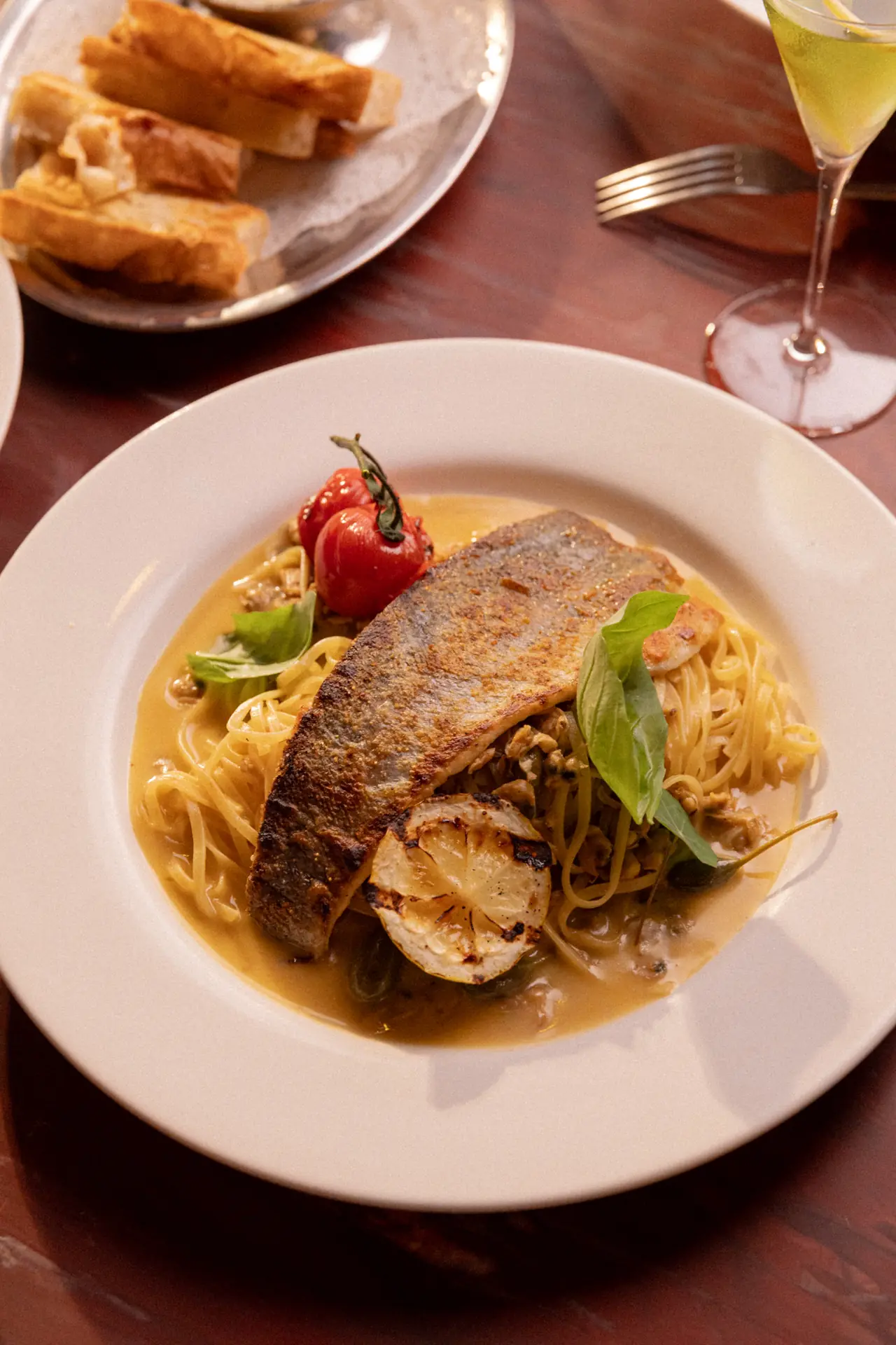 Filé de peixe dourado sobre espaguete com tomate e manjericão
